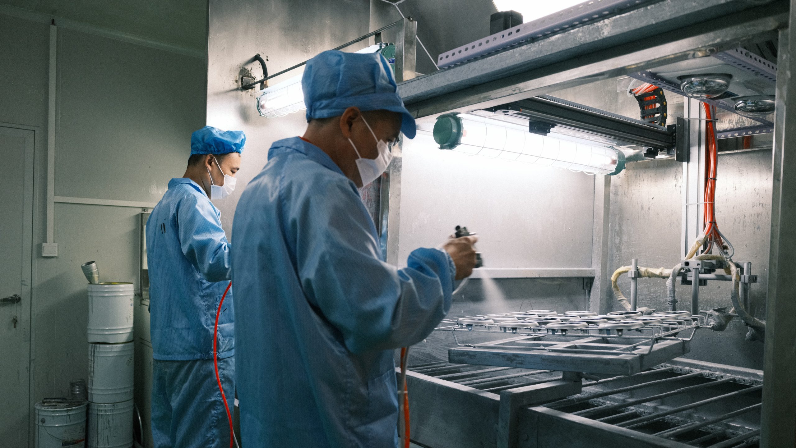 Technician performing manual surface spraying in a controlled booth.